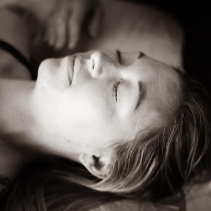 A monochrome headshot of a woman resting peacefully with her eyes closed
